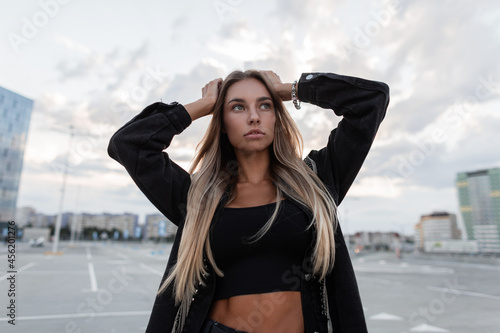 Stylish pretty serious woman in fashion black jeans jacket with black t-shirt walks in the city, urban female style outfit © alones