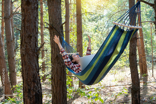 Freelance and working at nature. Woman freelancer works at notebook while lying on the hammock in the forest. Online business independent of the office.