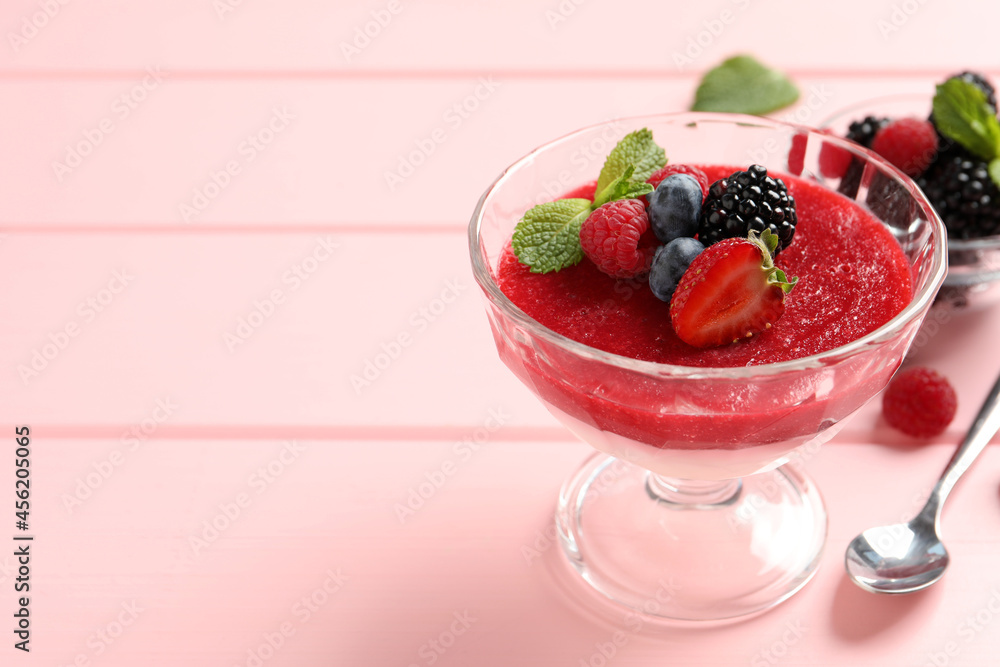 Delicious panna cotta with fruit coulis and fresh berries served on pink wooden table. Space for text Delicious panna cotta with fruit coulis and fresh berries served on pink wooden table. Space for text