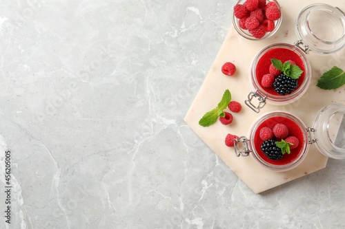 Delicious panna cotta with fruit coulis and fresh berries on light grey table, top view. Space for text