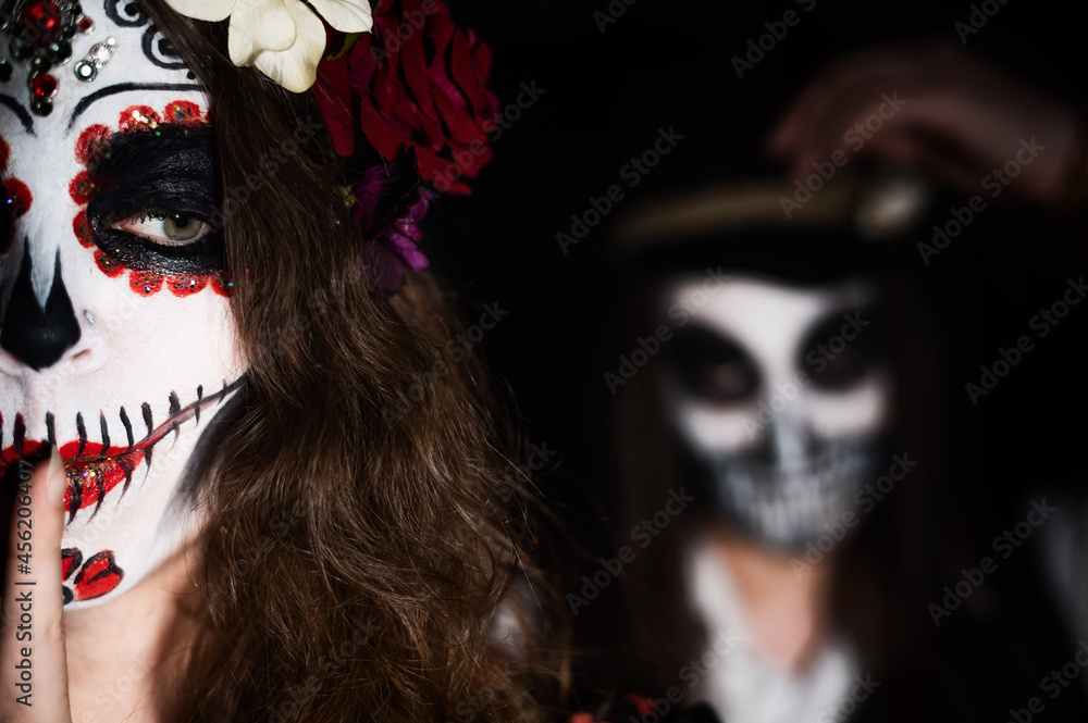 Woman in santa muerte costume and man in skeleton bodypainting for halloween.