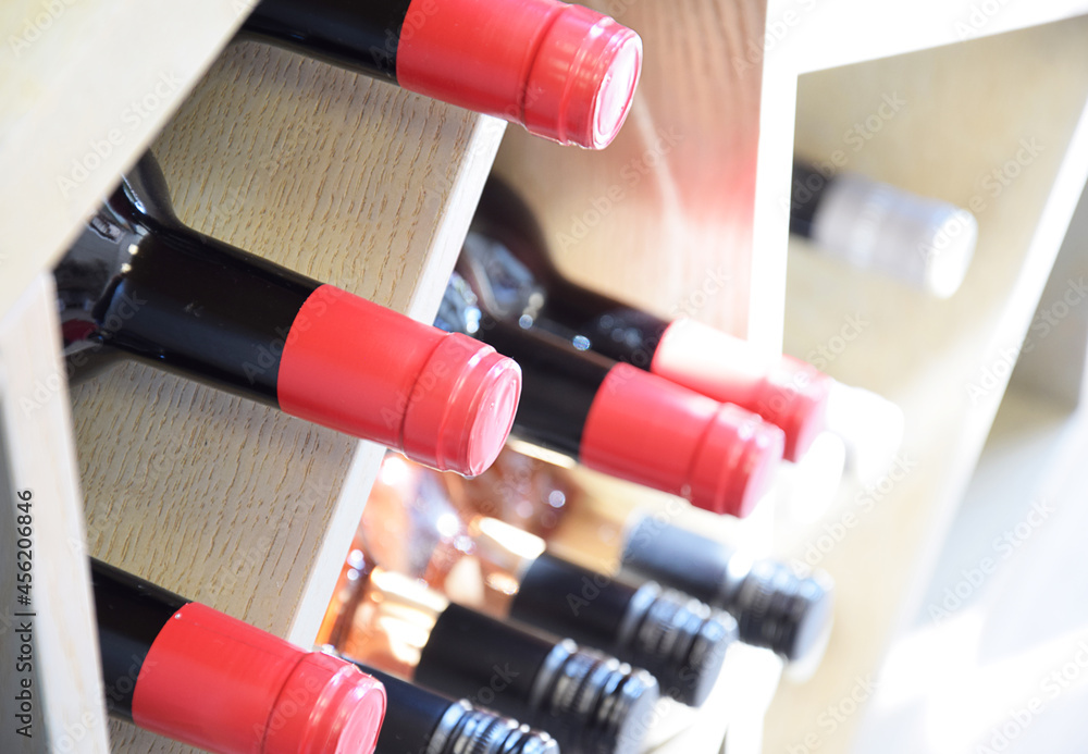 Wine bottles on wooden shelf in wine store and shining in the sun Wine bottles on wooden shelf in wine store and shining in the sun