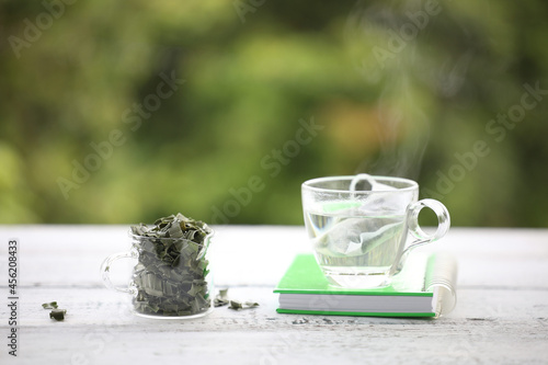 Pandan tea and leaves piles in small glass pitcher with green notebook photo