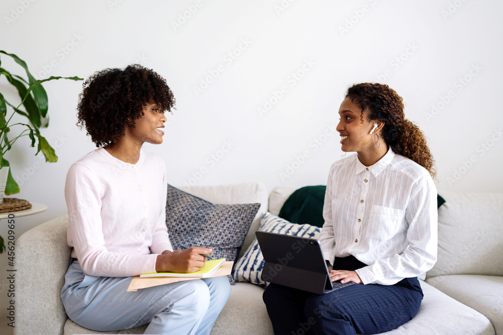 Two young business professional black women having interview conversation  wearing smart casual sitting on sofa using tablet Stock Photo | Adobe Stock