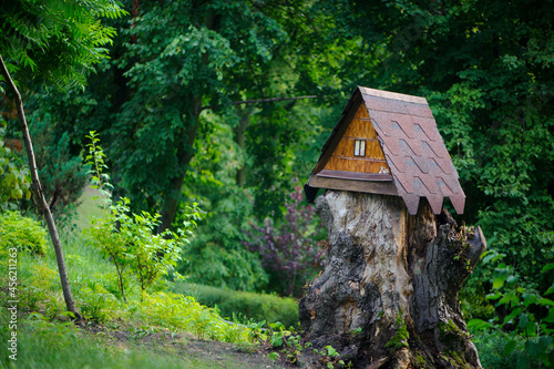 house in the forest for animals and birds. Wooden bird house in the summer park. on an tree stump. Old wooden feeder for birds on a tree, empty bird's feeder caring about wild birds in cold season. © Oleksandr Filatov