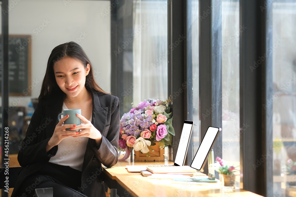 Portrait with Asian young businesswoman holding a hot coffee cup while sitting at counter bar in the cafe. Portrait with Asian young businesswoman holding a hot coffee cup while sitting at counter bar in the cafe.