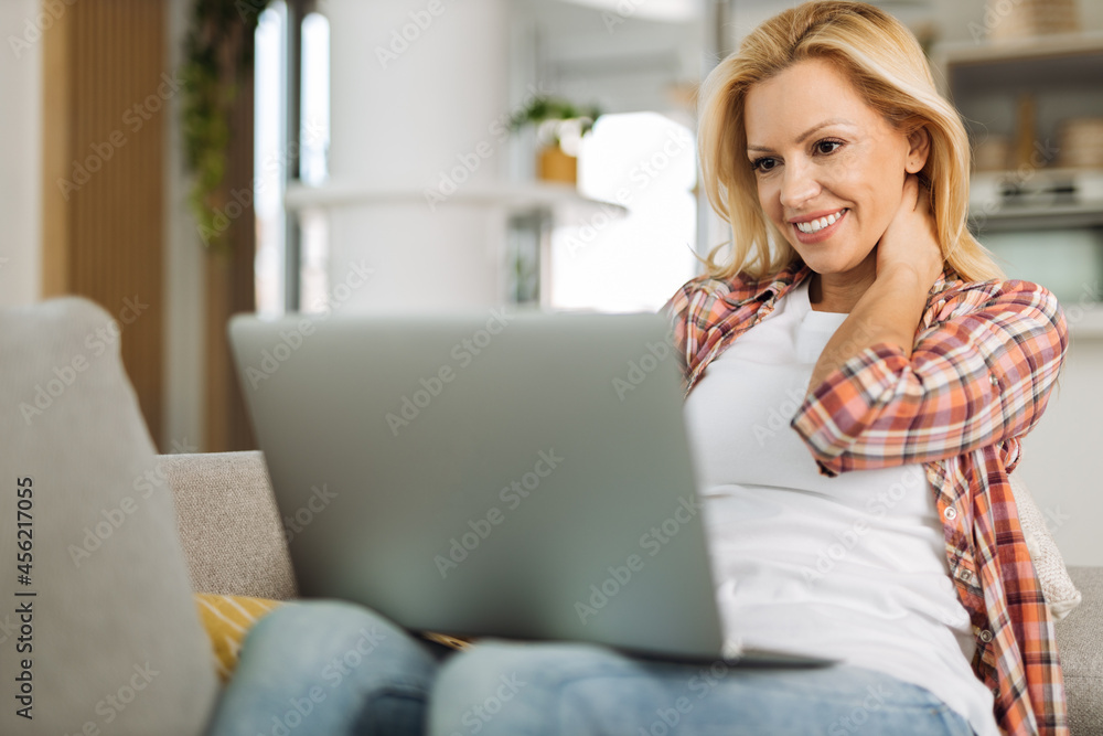 Young woman relaxing on sofa at home while using computer Young woman relaxing on sofa at home while using computer