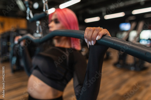 Young sports girl doing exercise on training apparatus machine in the gym, close up