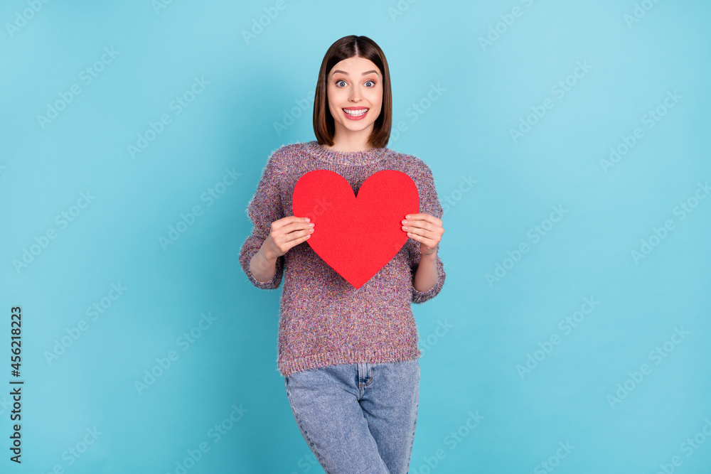 Photo of excited girlfriend lady hold red paper heart card wear knitted pullover isolated blue color background Photo of excited girlfriend lady hold red paper heart card wear knitted pullover isolated blue color background