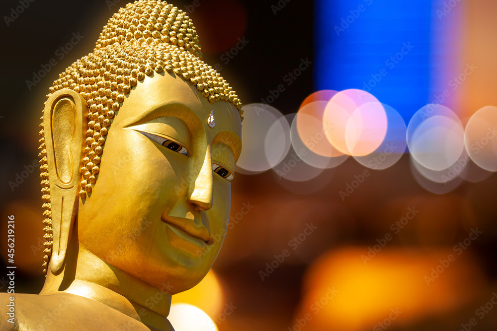Buddha face, elegrant face of golden big buddha on blur bokeh background