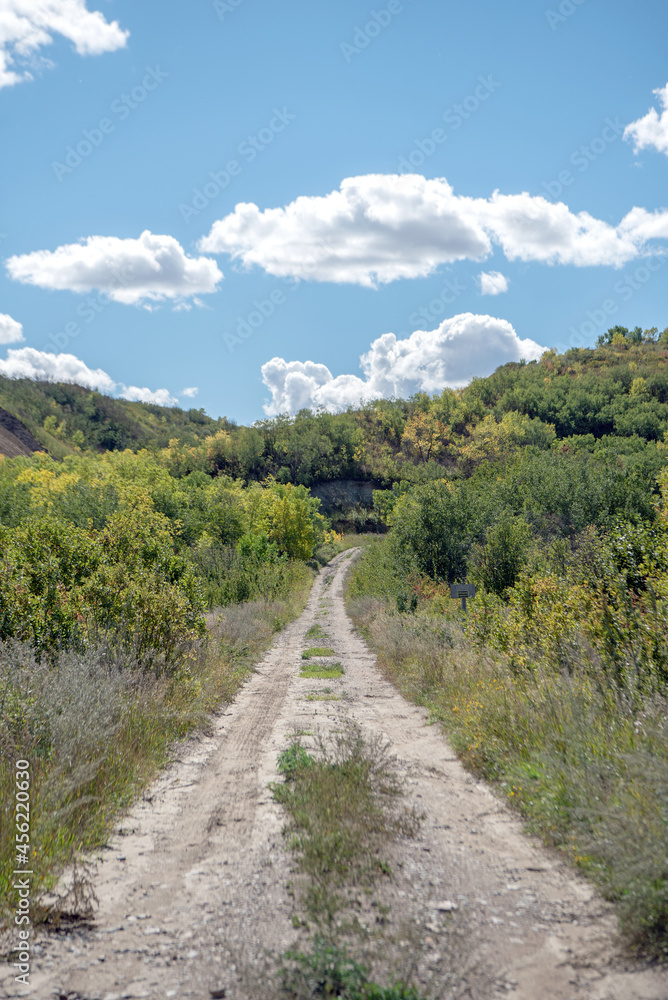 Dirt road in the rural countryside of the Qu'Appelle Valley in the Saskatchewan prairies of Canada on a bright early autumn day
