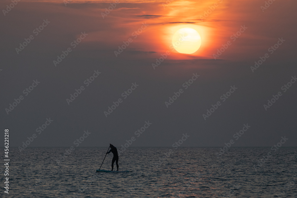 paddle boarder returning to the shore at sunset