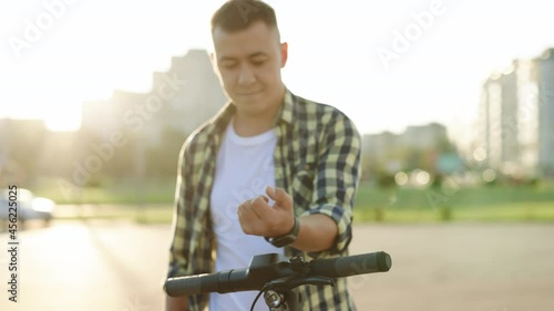 Man rent rental take electric kick scooter in sharing parking lot, tourist smartwatch application. Driving ecology transportation. Man on electric scooter mobility. E-scooter eco transport