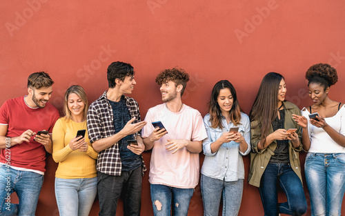 Young friends using mobile smartphone outdoor - Millennial generation having fun with new trends social media apps - Youth technology people addicted - Red background