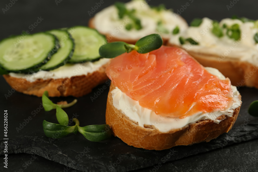 Delicious sandwiches with cream cheese and other ingredients on black table, closeup Delicious sandwiches with cream cheese and other ingredients on black table, closeup