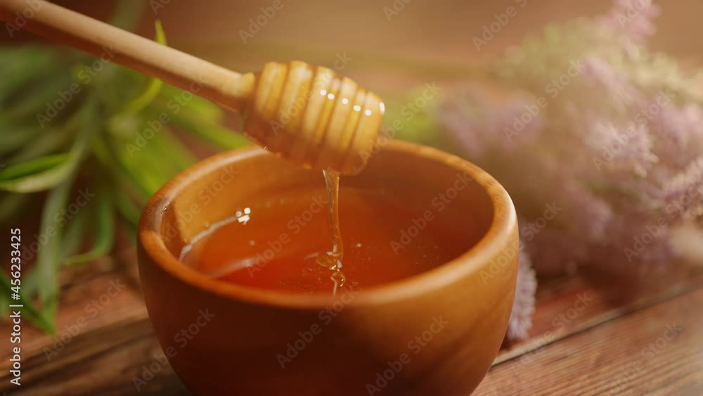 A person is dipping wooden spoon in honey. Golden fresh honey is pouring from stick. Organic beekeeping. Concept of healthy organic food and sweet meals. A person is dipping wooden spoon in honey. Golden fresh honey is pouring from stick. Organic beekeeping. Concept of healthy organic food and sweet meals.