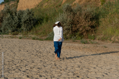 Сute teenage girl or woman wearing blue pants, white shirt, white bandana on the beach nature landscape fresh air beach. Natural beauty. lifestyle, real people, funny, dance. © MartaKlos