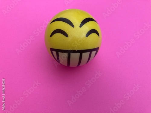 Pelota happy face amarillo sobre fondo rosa