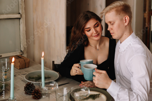 A man and a woman in love in elegant outfits congratulate each other  give gift boxes to each other  celebrate winter Christmas holidays on a romantic date at home  selective focus