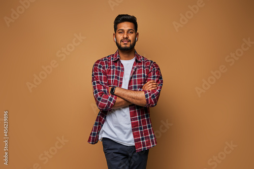 Photography Stylish handsome indian student with crossed arms in tshirt on pastel background