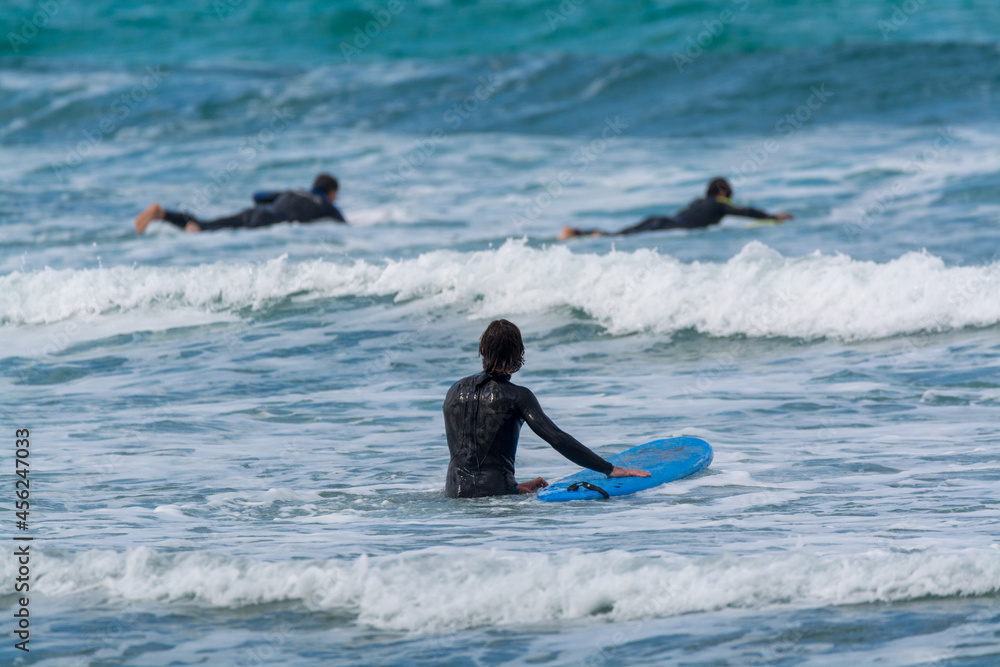 Surfers train in cold water of Atlantic ocean on famous surf Famara beach, Lanzarote, Canary islands, Spain Surfers train in cold water of Atlantic ocean on famous surf Famara beach, Lanzarote, Canary islands, Spain
