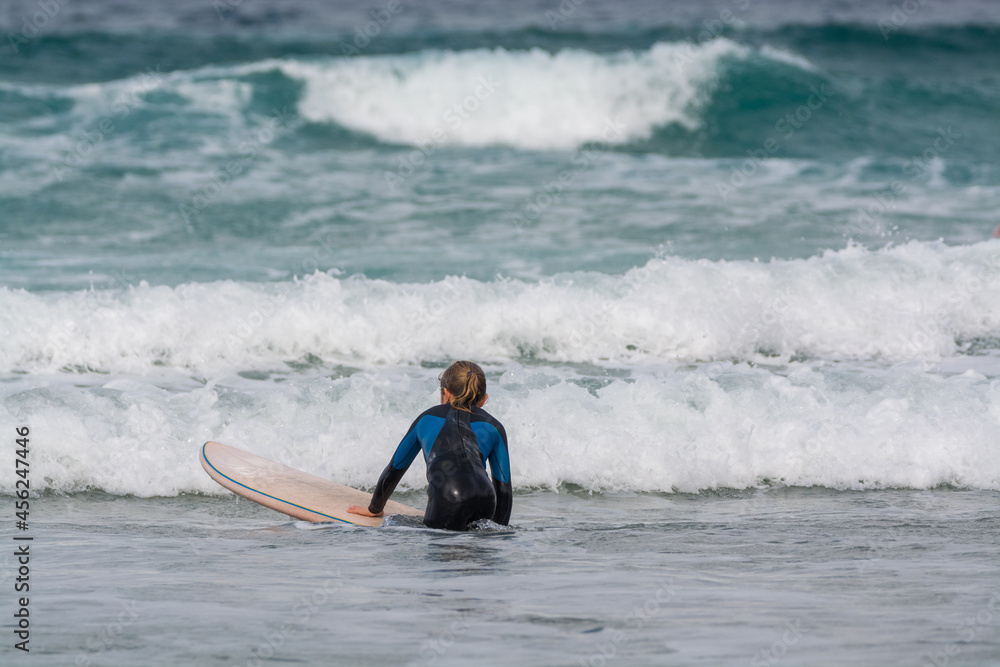 Surfers train in cold water of Atlantic ocean on famous surf Famara beach, Lanzarote, Canary islands, Spain Surfers train in cold water of Atlantic ocean on famous surf Famara beach, Lanzarote, Canary islands, Spain