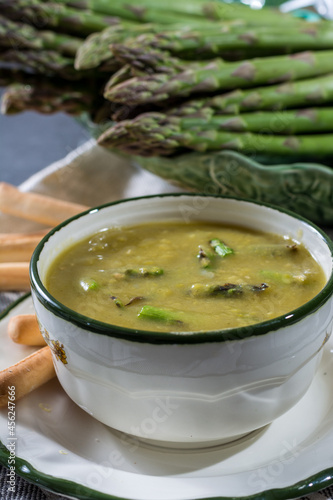 Bowl with creme soup made from fresh green asparagus vegetables close up