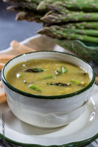 Bowl with creme soup made from fresh green asparagus vegetables close up
