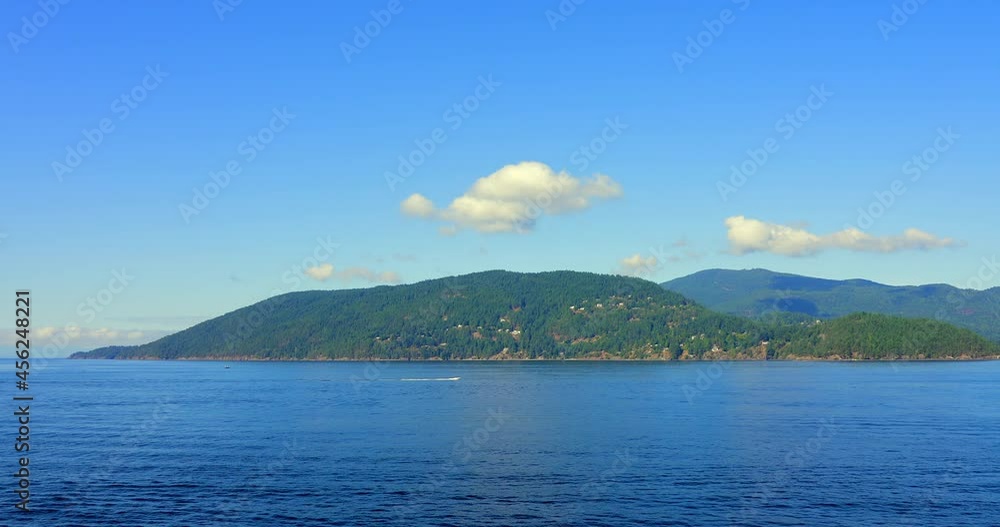 Establishing shot of ocean view with mountains, blue sky and white clouds in slow motion at summer day in Vancouver, Canada, North America. Day time on Sept 2021. Still camera. ProRes 422 HQ. Establishing shot of ocean view with mountains, blue sky and white clouds in slow motion at summer day in Vancouver, Canada, North America. Day time on Sept 2021. Still camera. ProRes 422 HQ.