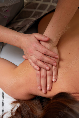 Massagist performing back massage to female client.
