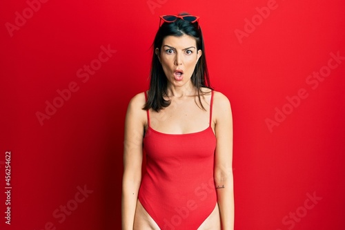 Wallpaper Mural Young hispanic woman wearing swimsuit and sunglasses scared and amazed with open mouth for surprise, disbelief face Torontodigital.ca