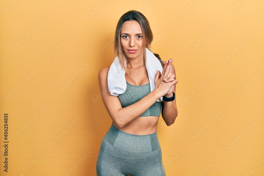 Beautiful hispanic woman wearing sportswear and towel holding symbolic gun with hand gesture, playing killing shooting weapons, angry face Beautiful hispanic woman wearing sportswear and towel holding symbolic gun with hand gesture, playing killing shooting weapons, angry face
