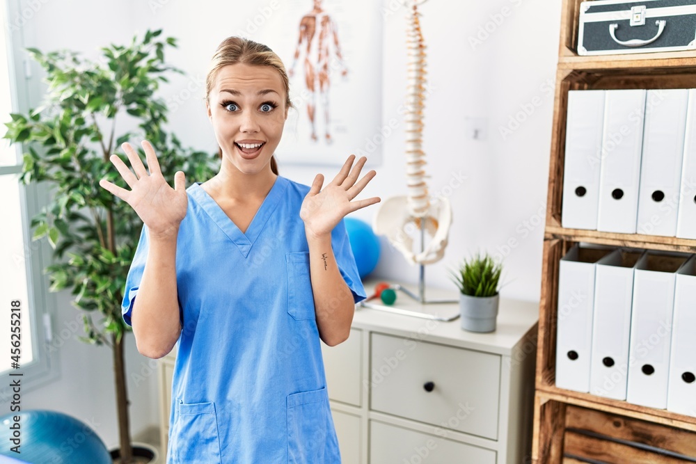 Young caucasian woman working at pain recovery clinic celebrating crazy and amazed for success with arms raised and open eyes screaming excited. winner concept Young caucasian woman working at pain recovery clinic celebrating crazy and amazed for success with arms raised and open eyes screaming excited. winner concept