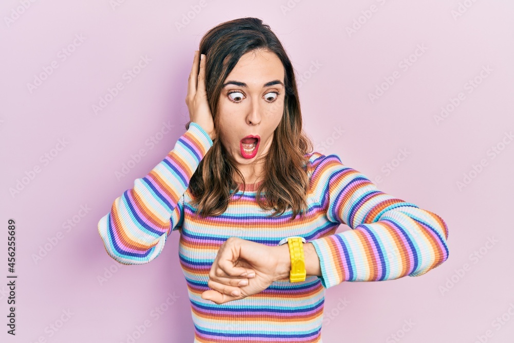 Young hispanic girl wearing casual clothes looking at the watch time worried, afraid of getting late Young hispanic girl wearing casual clothes looking at the watch time worried, afraid of getting late