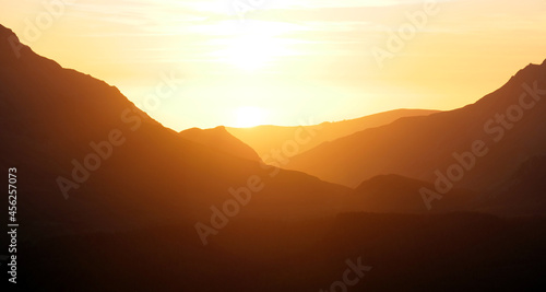 Stunning golden orange sunset in Snowdonia mountains, background.