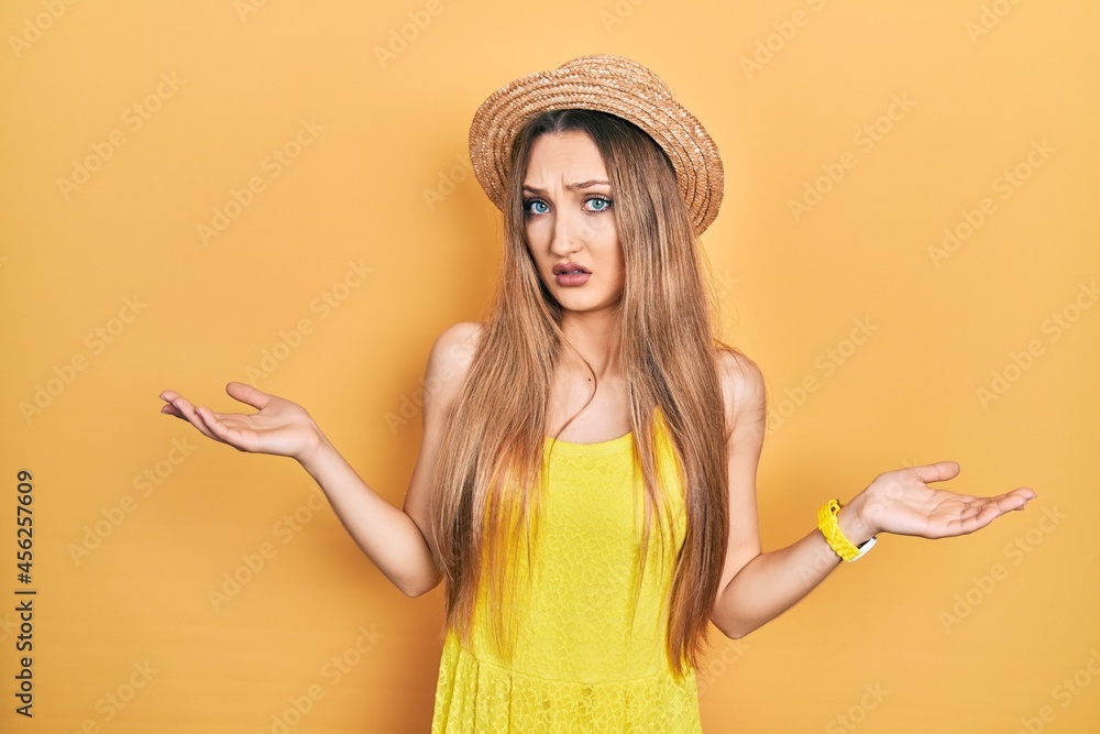Young blonde girl wearing summer hat clueless and confused with open arms, no idea concept. Young blonde girl wearing summer hat clueless and confused with open arms, no idea concept.