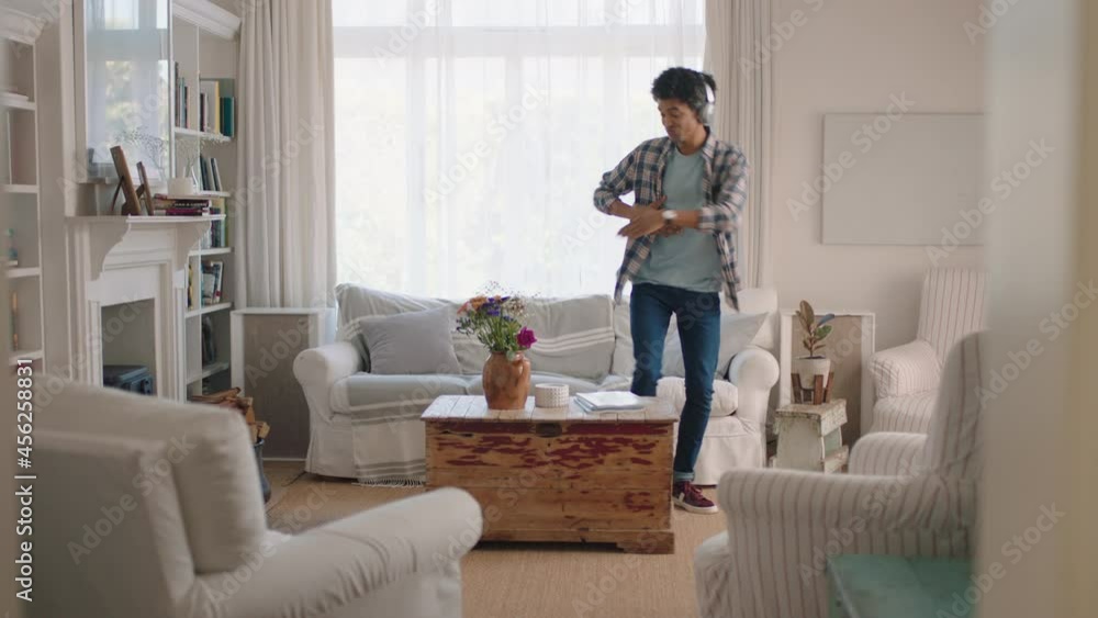 happy young man dancing at home celebrating success listening to music wearing headphones having fun dance in living room on weekend happy young man dancing at home celebrating success listening to music wearing headphones having fun dance in living room on weekend