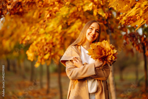 Happy woman having fun and playing with autumn yellow leaves in park. Lifestyle. Relax  nature concept. Autumn style.