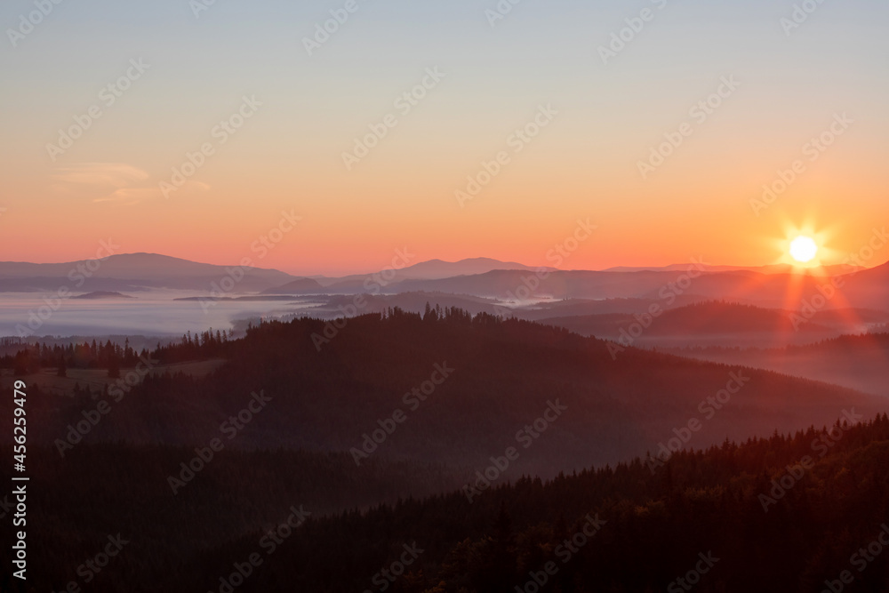 landscape with sunrise over the mountains and fog in the valleys