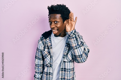 Young african american man wearing casual clothes smiling with hand over ear listening and hearing to rumor or gossip. deafness concept.