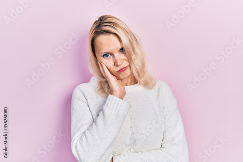 Beautiful caucasian blonde woman wearing casual winter sweater thinking looking tired and bored with depression problems with crossed arms.