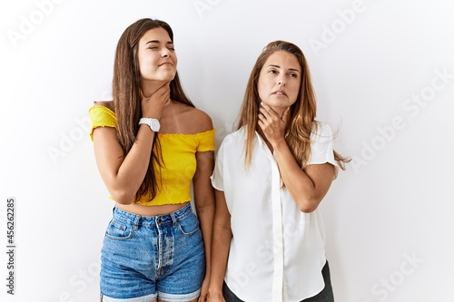 Mother and daughter together standing together over isolated background touching painful neck, sore throat for flu, clod and infection