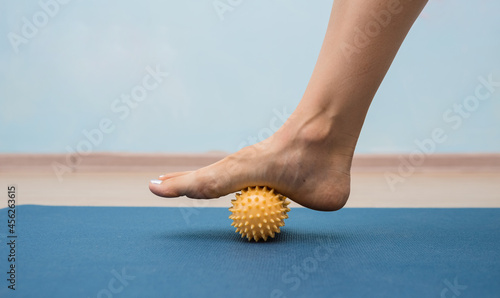 close-up of a leg rolling a yellow massage ball on a mat