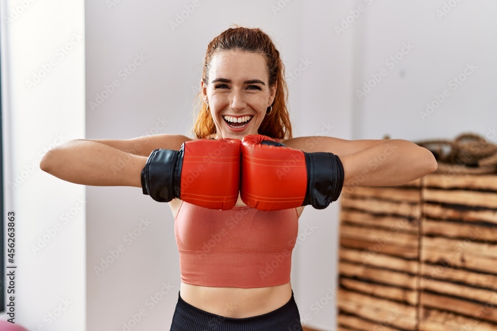 Young redhead woman using boxing gloves smiling and laughing hard out loud because funny crazy joke.