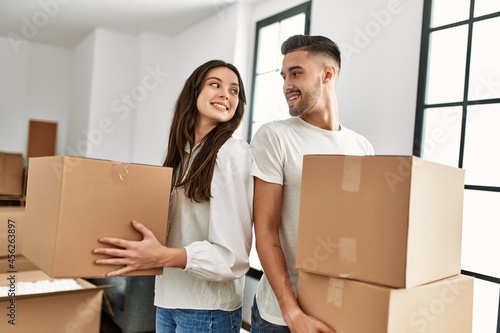 Young hispanic couple smiling happy holding cardboard boxes moving at new home. © Krakenimages.com