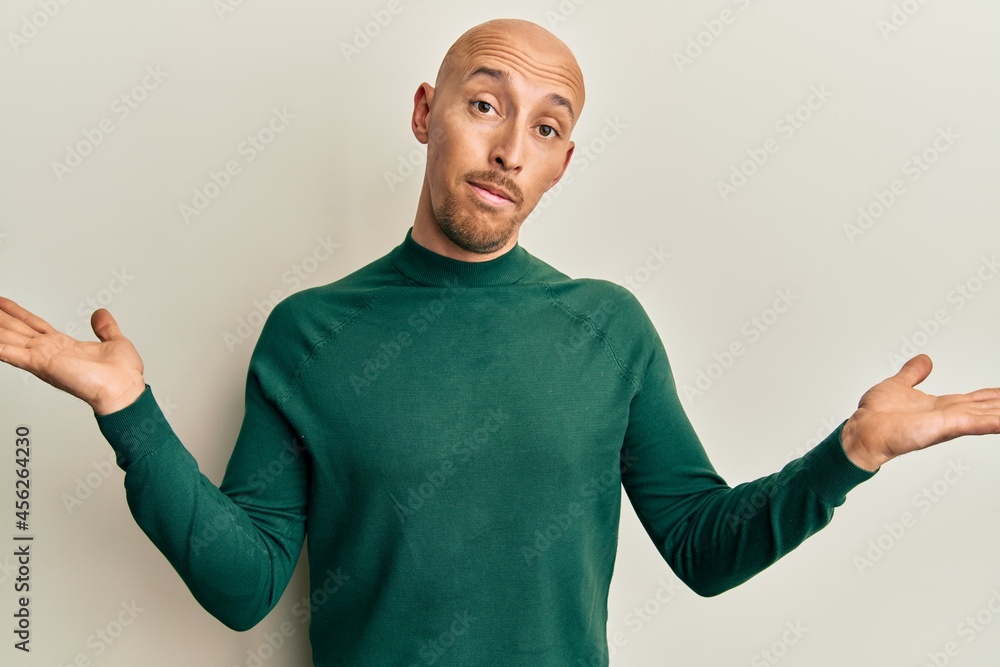 Bald man with beard wearing casual turtleneck sweater clueless and confused with open arms, no idea and doubtful face. Bald man with beard wearing casual turtleneck sweater clueless and confused with open arms, no idea and doubtful face.