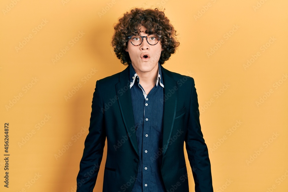 Fototapeta premium Handsome young man wearing business jacket and glasses scared and amazed with open mouth for surprise, disbelief face