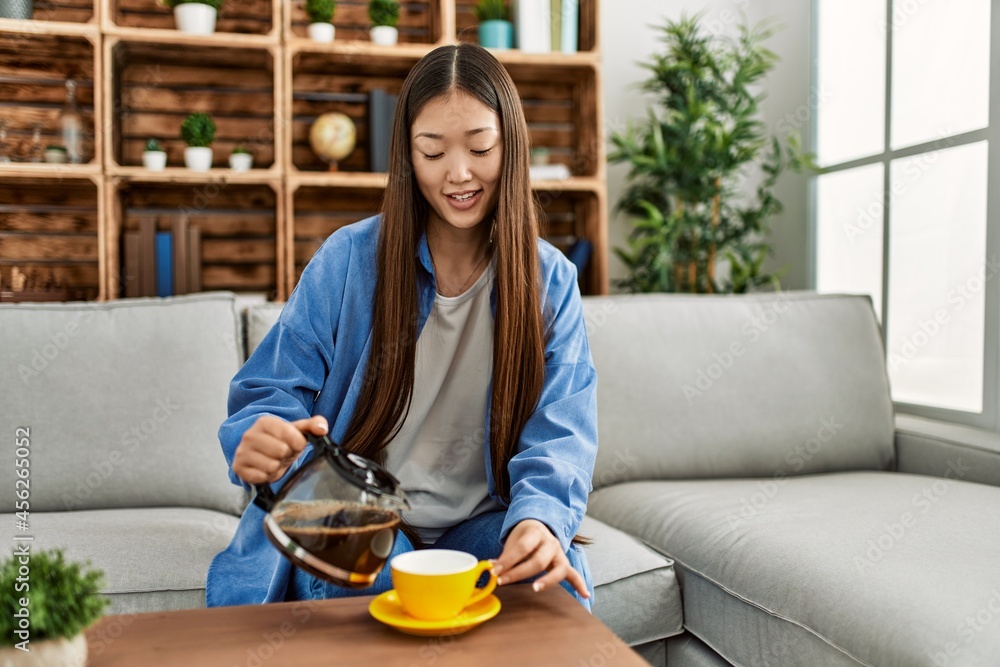 Young chinese girl drinking coffee sitting on the sofa at home. Young chinese girl drinking coffee sitting on the sofa at home.
