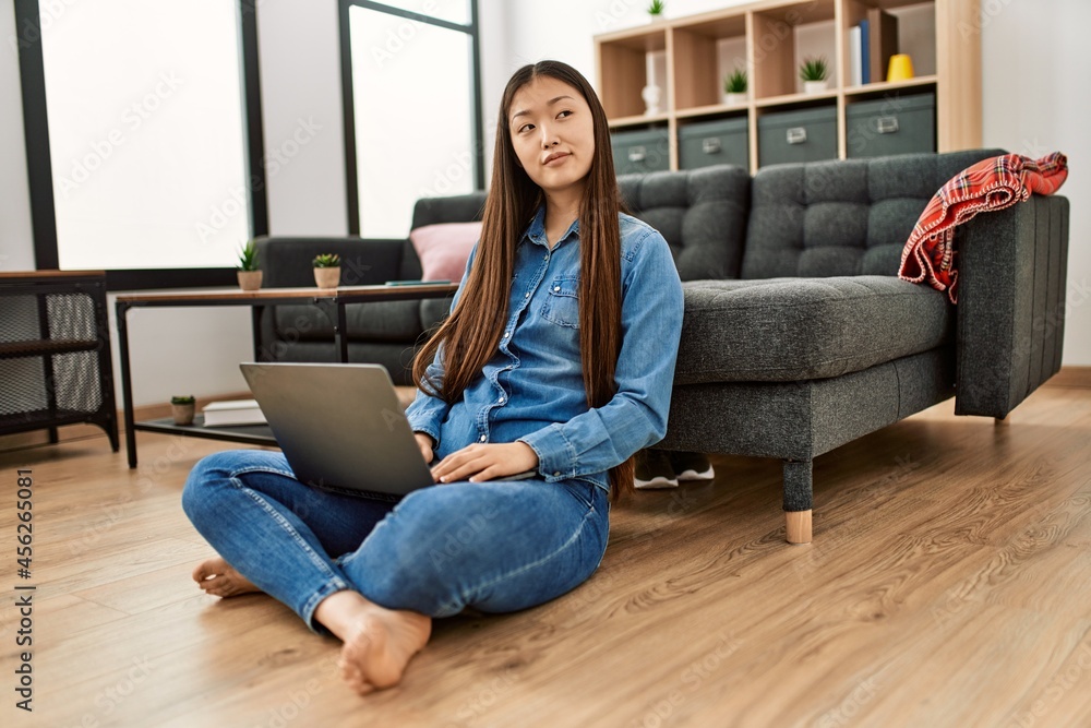 Young chinese girl using laptop sitting on the floor at home. Young chinese girl using laptop sitting on the floor at home.