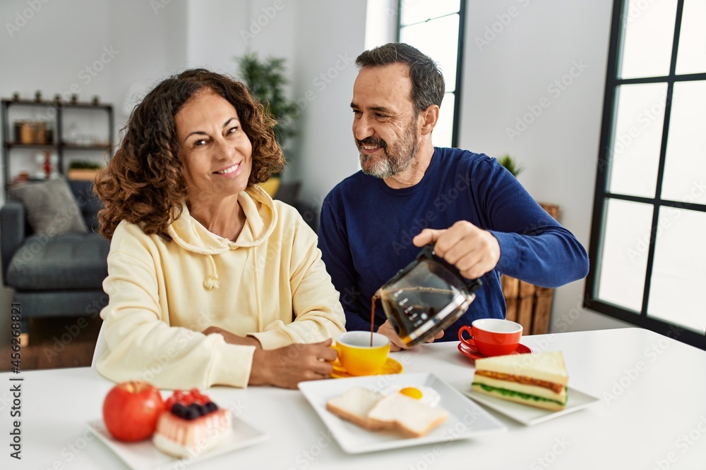 Middle age hispanic couple smiling happy sitting on the table having breakfast at home. Middle age hispanic couple smiling happy sitting on the table having breakfast at home.